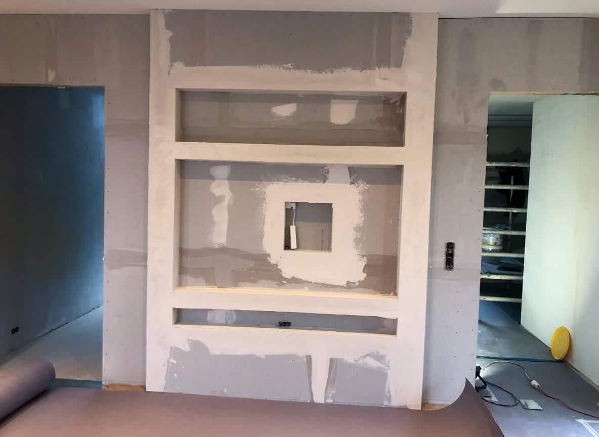 Før- og eftermaling af væg med integrerede reoler i husdesign, professionelle malere i aktion.